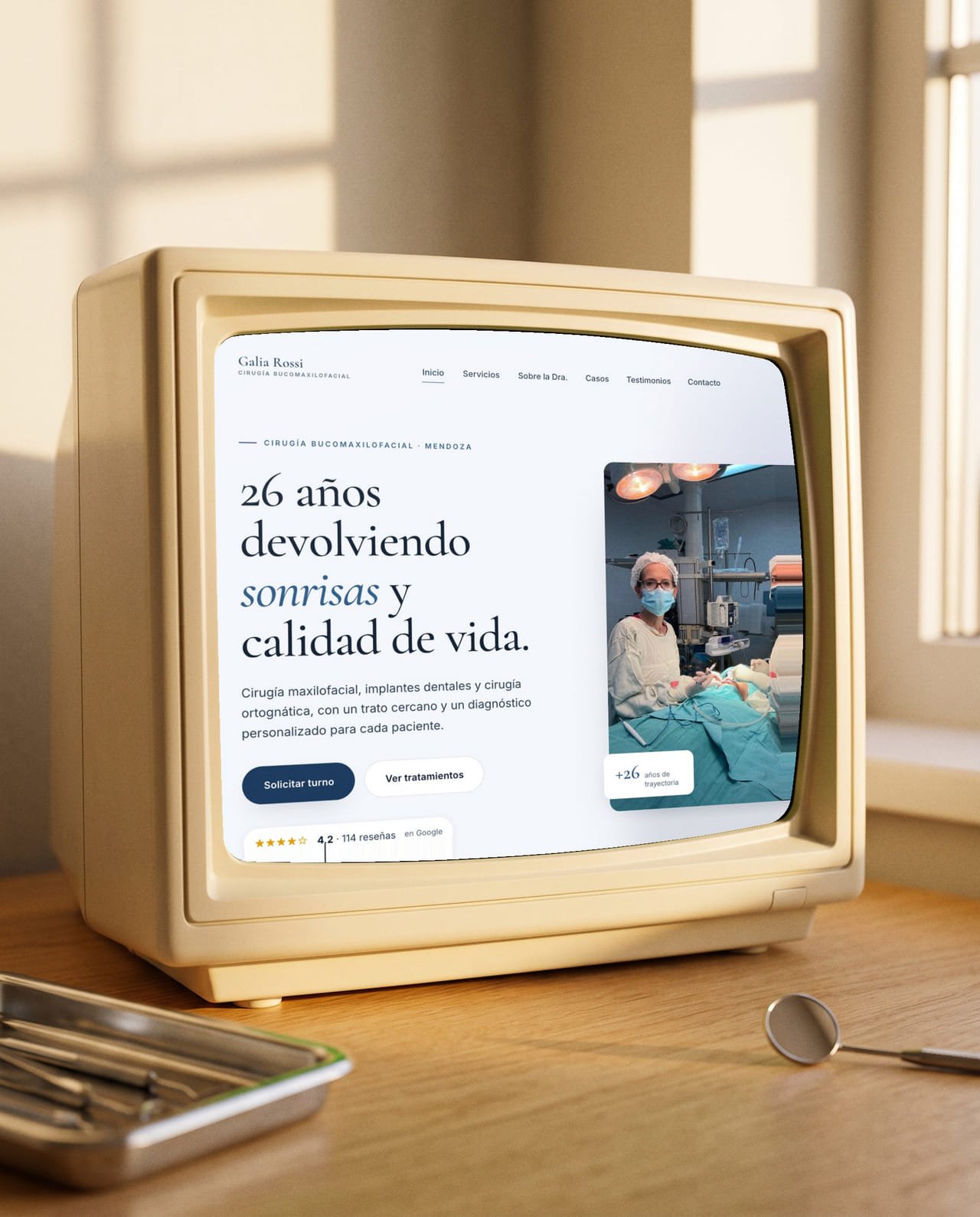 El sitio de la Dra. Galia Rossi en un televisor de tubo sobre un escritorio de consultorio, junto a una bandeja de instrumental